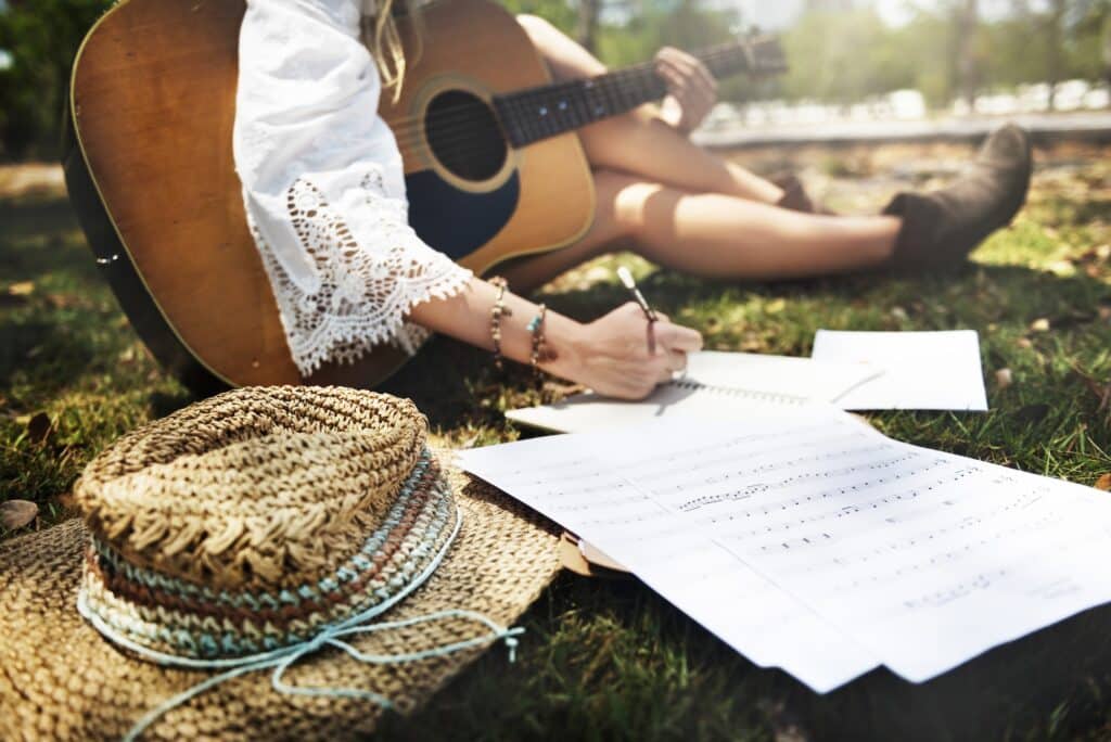 Closeup of woman guitarist sitting composing music in the park